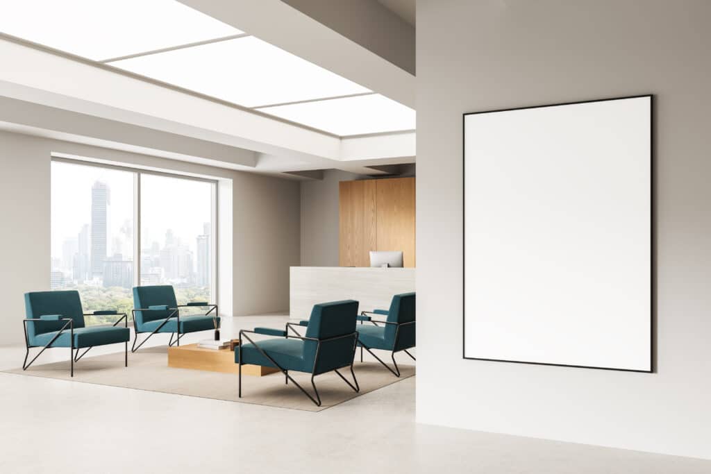 Hall d'accueil moderne avec fauteuils design et vue urbaine Bureau d'accueil moderne avec fauteuils turquoise, grande baie vitrée vue ville, et cadre blanc vide sur mur beige.