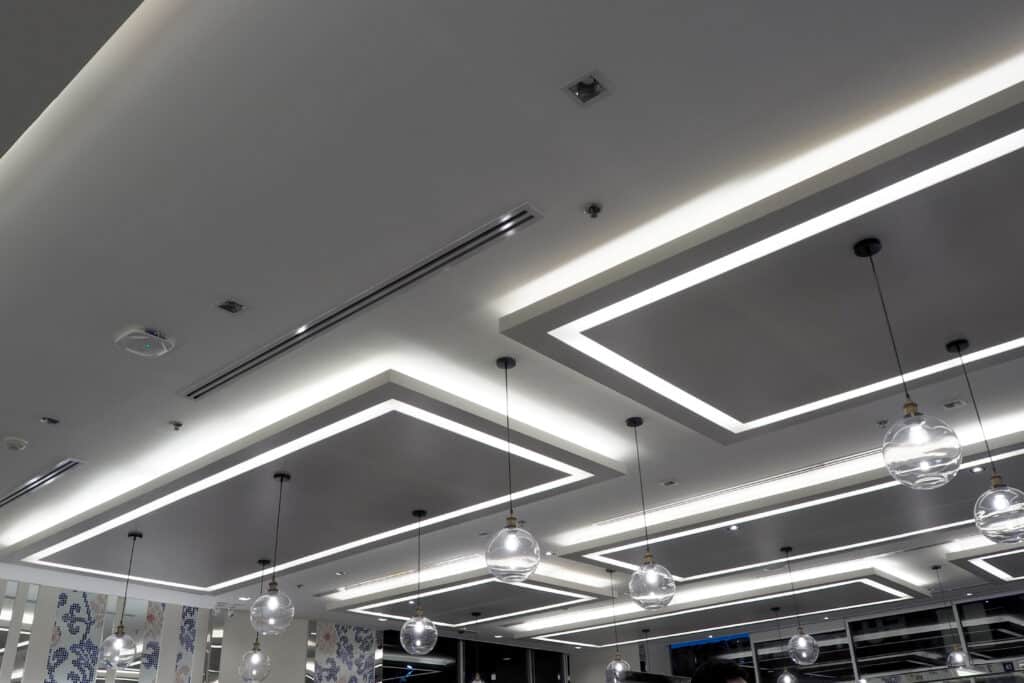 Plafonnier moderne LED et suspensions salon design Plafond moderne avec éclairage indirect à LED formant des rectangles lumineux et suspensions à ampoules sphériques en verre.
